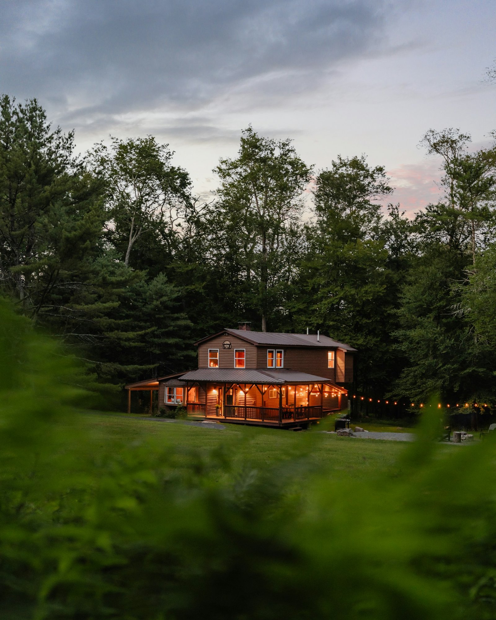 A house lit up at dusk in the woods