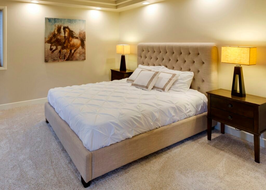 Cozy bedroom with a made bed, two nightstands and warm lamps.