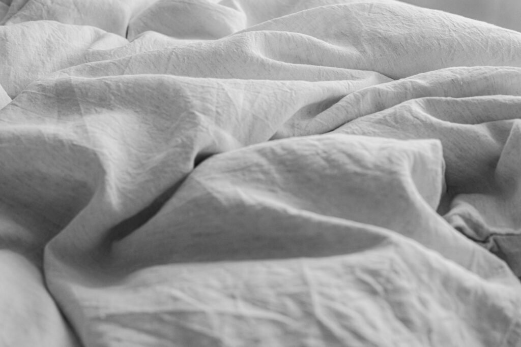 Soft white linen sheets in gentle folds.