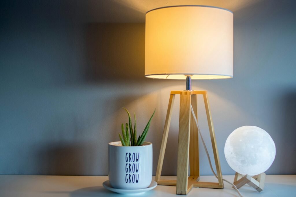 Tripod table lamp and small plant on a bedside table.