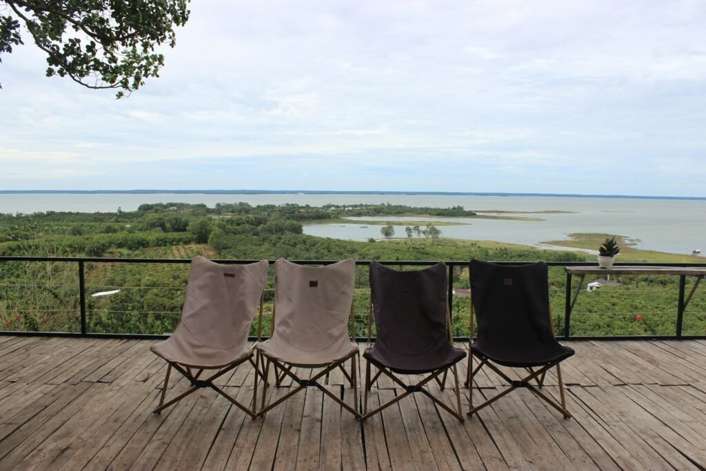 Folding camp chairs on a wooden deck above a lake.