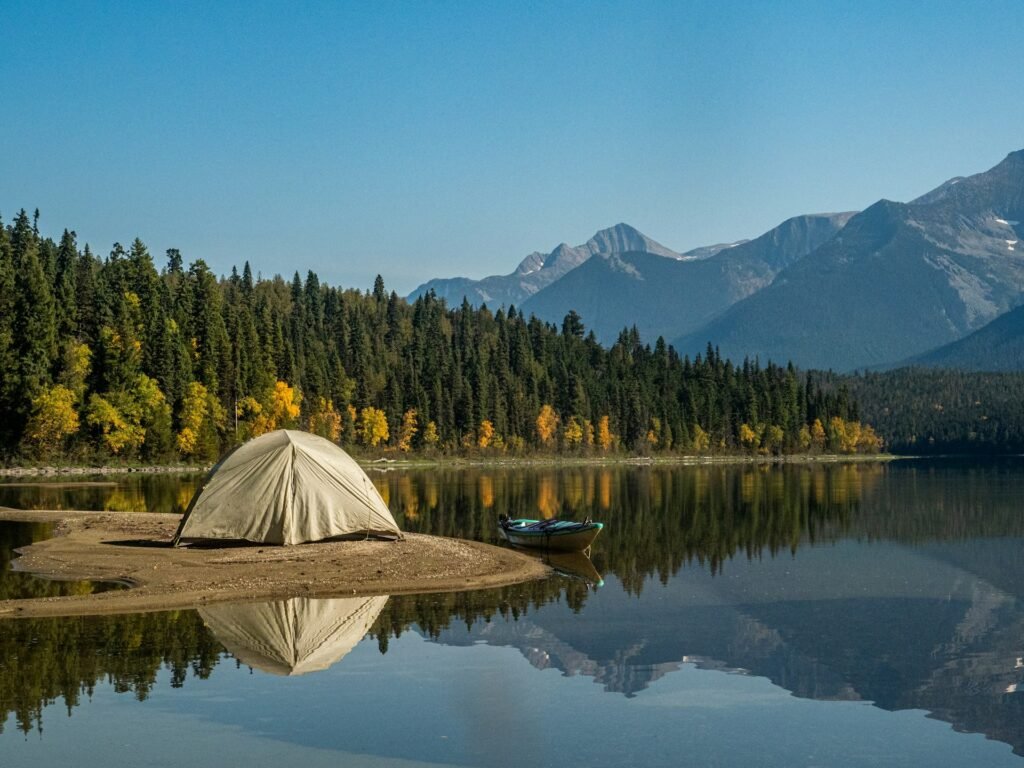 White tent beside a lake with trees and mountains