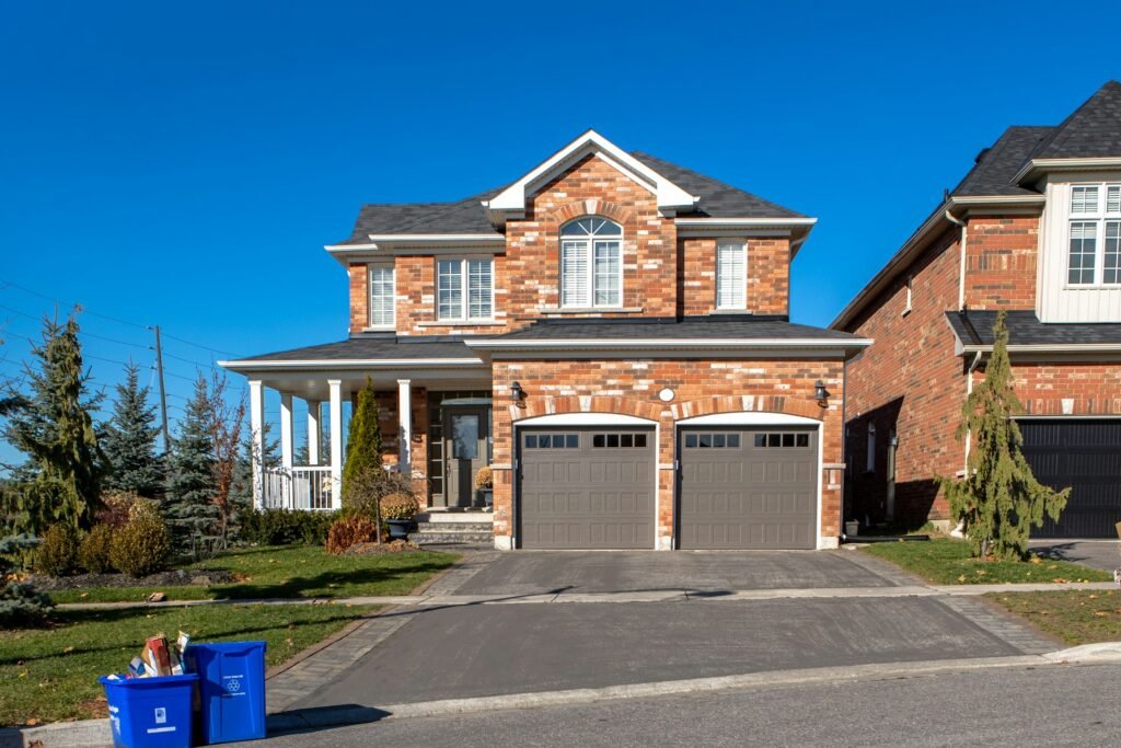 Brick house with a two-car garage and driveway under a blue sky.