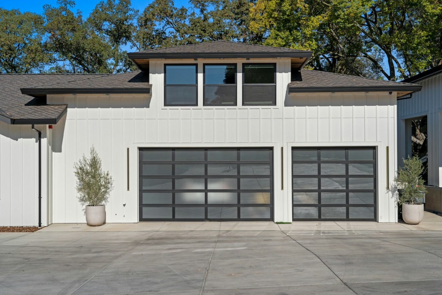 Two black glass garage doors on a modern white house
