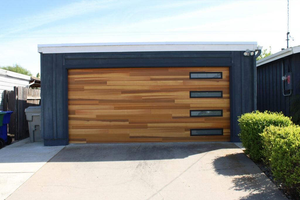 Wood-panel garage door with narrow windows on a dark modern home