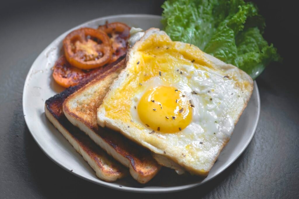 Toasted bread with a fried egg and tomato on a plate.