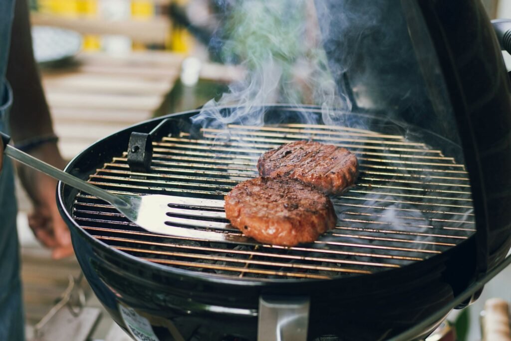 Meat searing on a round charcoal grill.