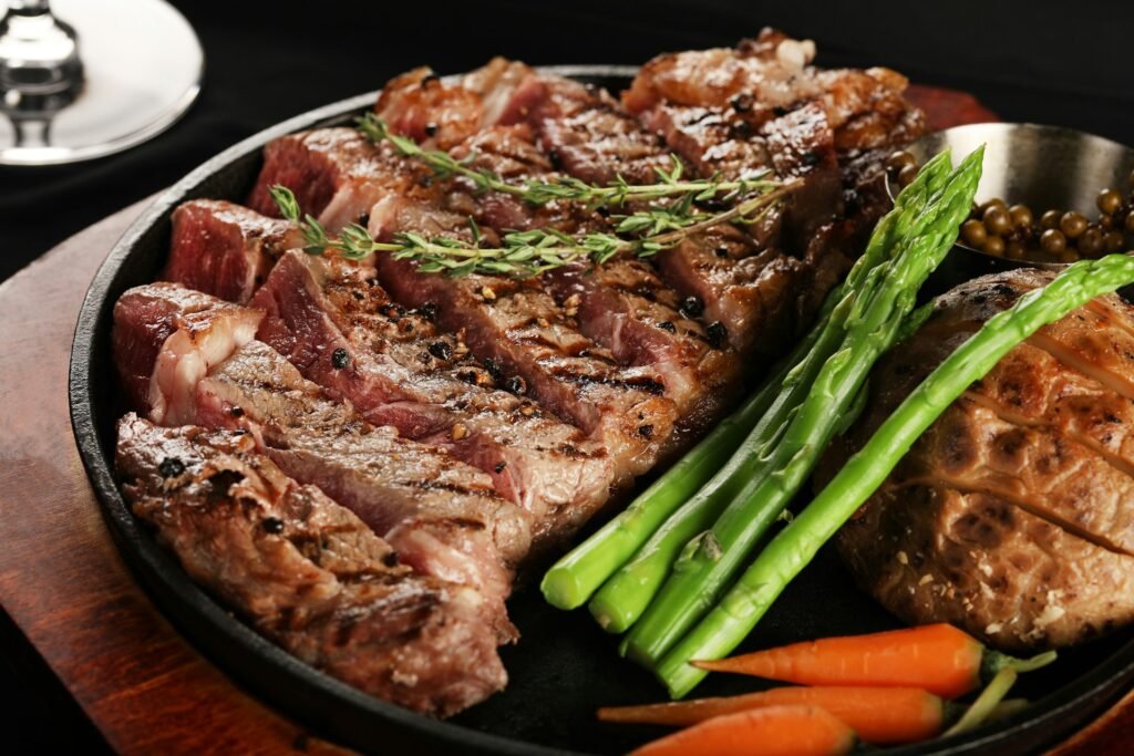 Sliced grilled steak with asparagus on a dark plate.