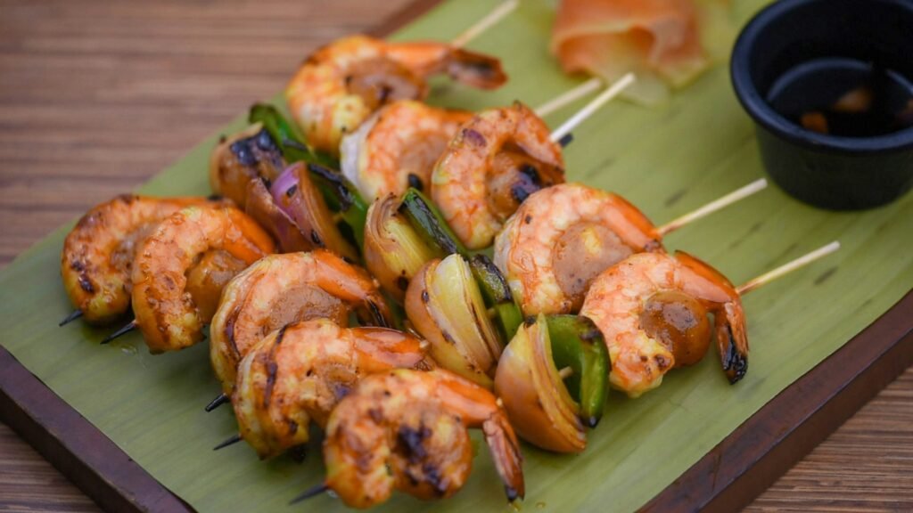 Grilled shrimp and vegetable skewers on a green plate.