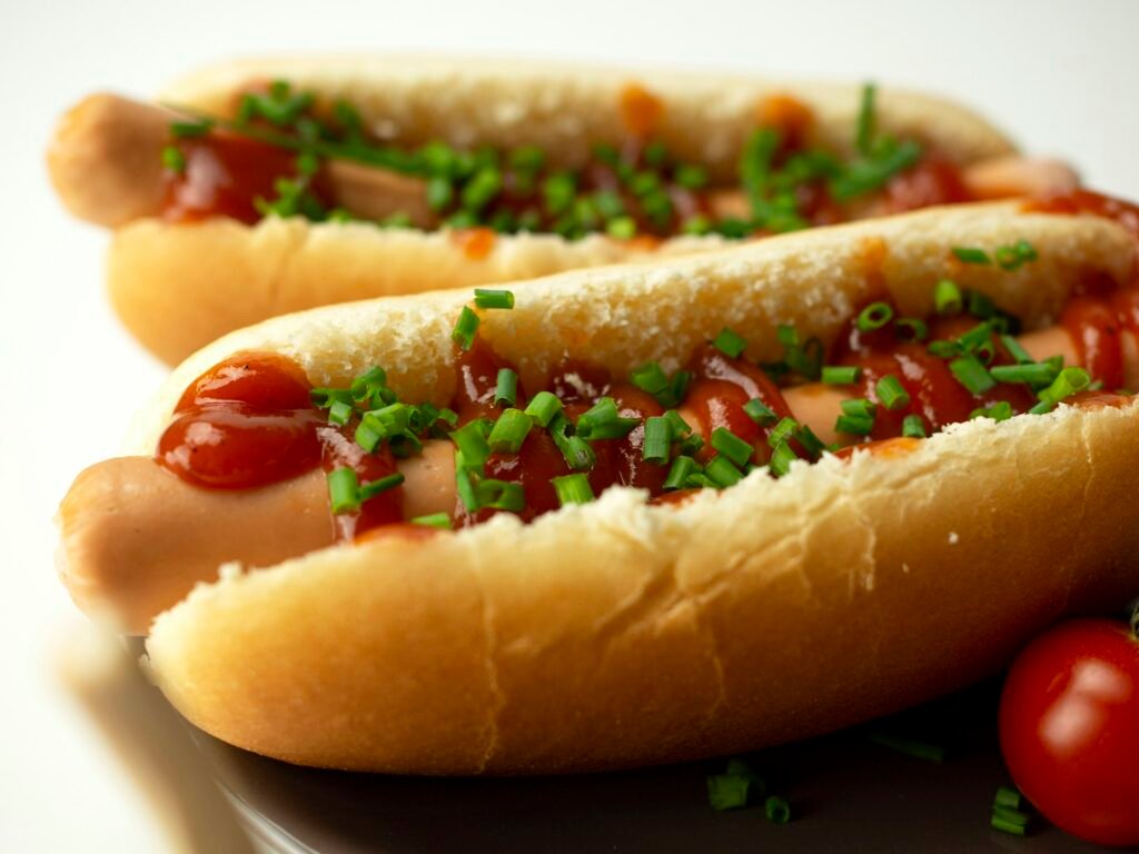 Grilled hot dog with toppings in a bun.