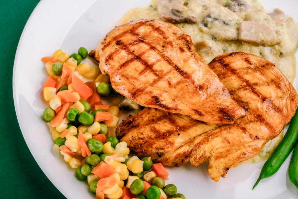 Grilled chicken breasts with a fresh salad on a white plate.