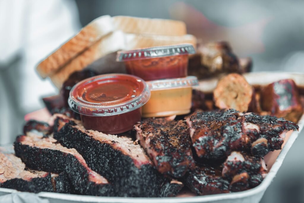 Sliced smoked brisket and ribs served on a tray with sauces.