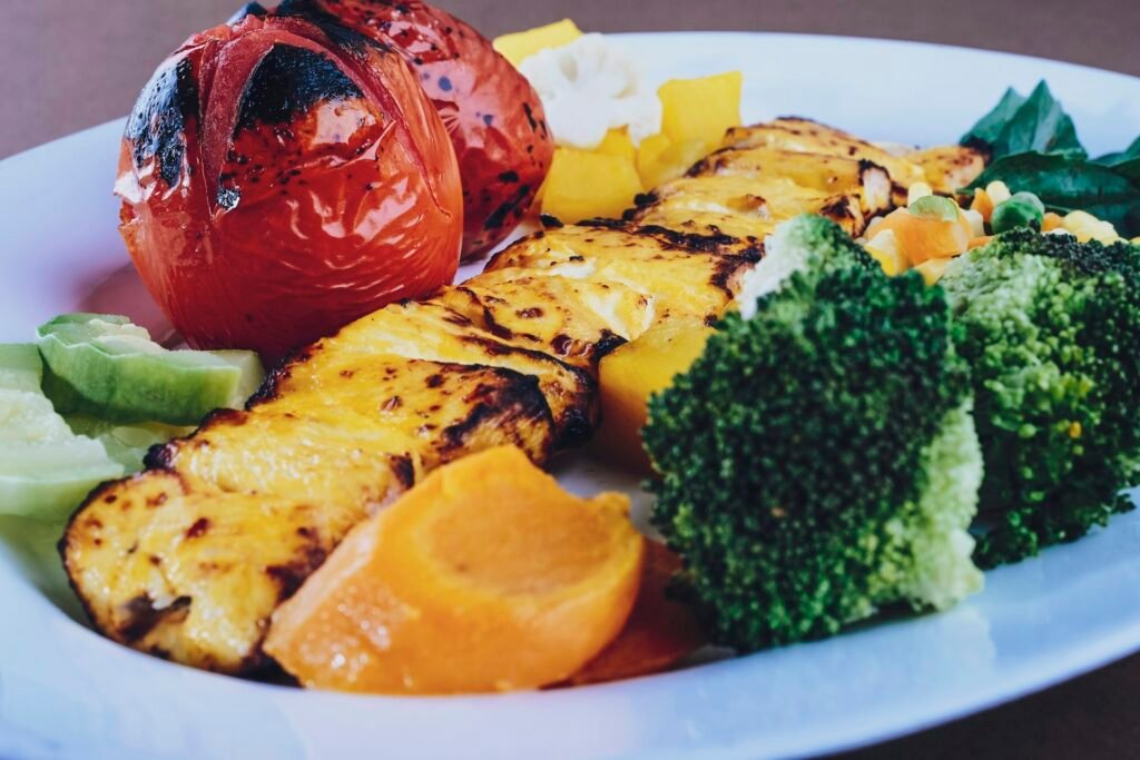 Grilled pineapple, tomato and broccoli on a white plate.