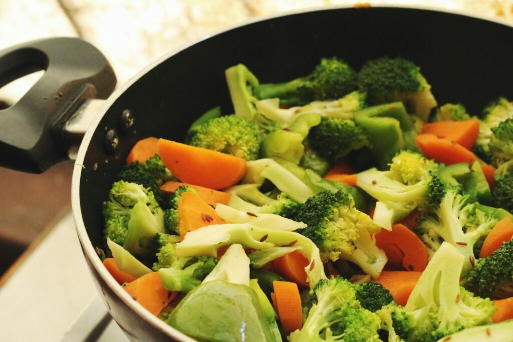 Broccoli, carrots and peppers cooking in a pan.