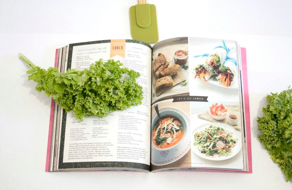 Open cookbook with fresh herbs on a white surface.