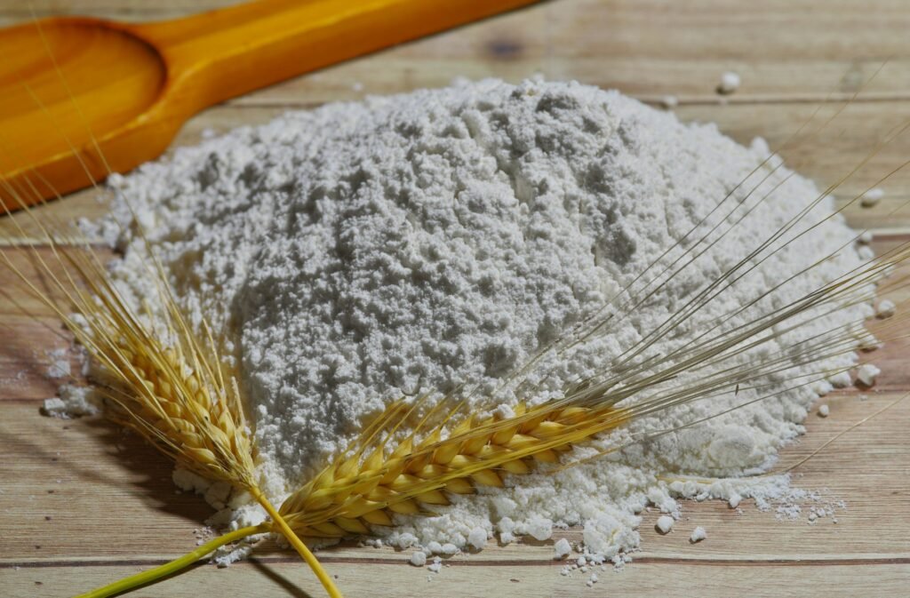 Flour and wheat stalks on a rustic wooden table.