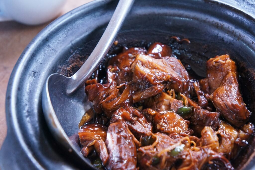 Slow-cooked meat in a dark pot with a serving spoon.