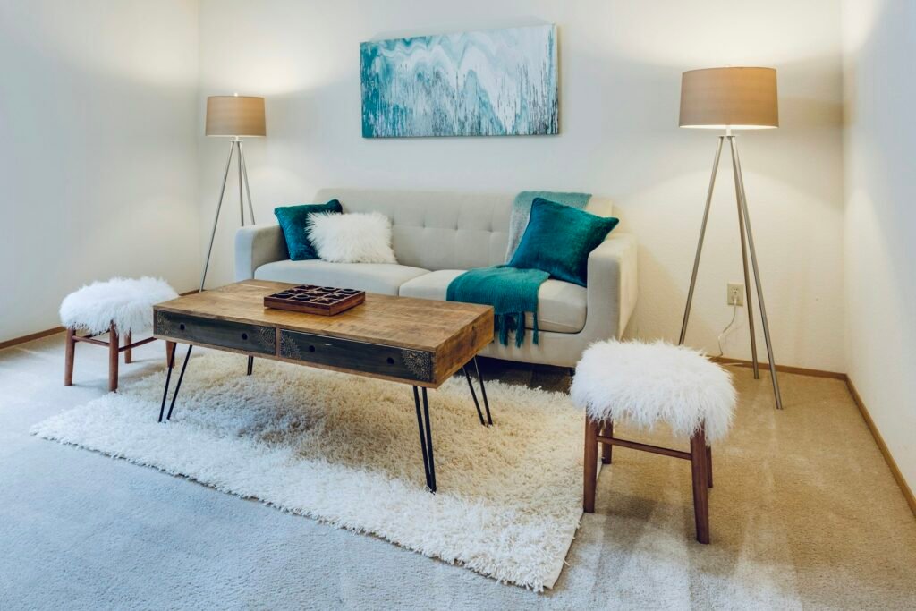 Bright living room with a sofa, teal pillows and a wooden coffee table.