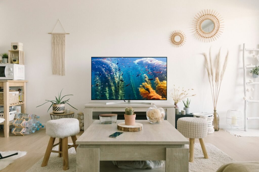 Airy living room with a TV, plants and a white table.