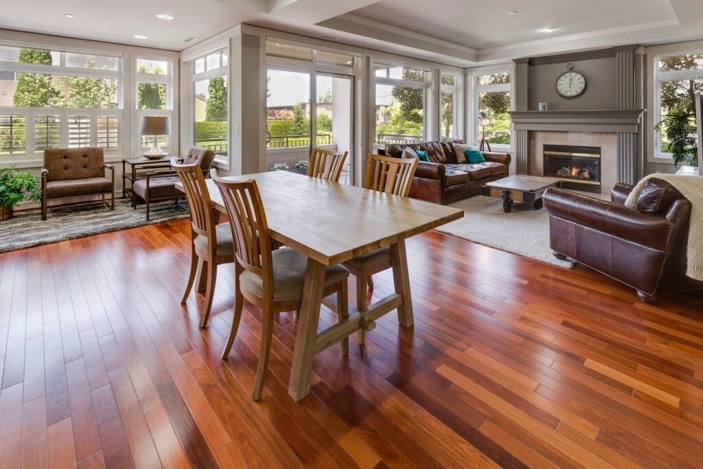 Sunlit living room with a hardwood floor, dining table and sitting area.