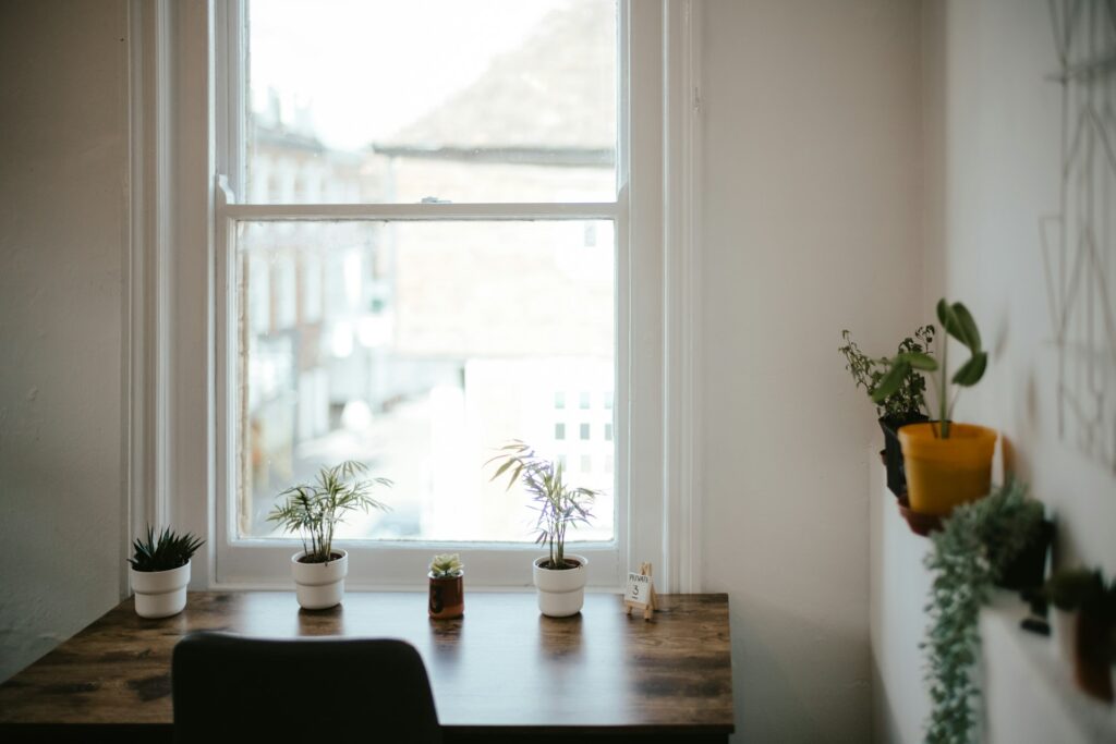 Home office desk and chair beside bright windows.