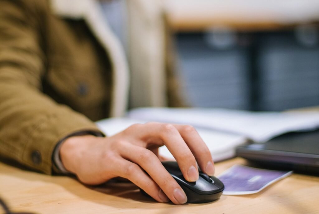 Hand resting on a computer mouse at a desk.