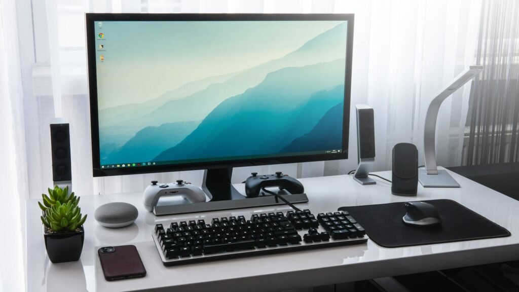 Tidy desk with a monitor, keyboard and speakers on a white desk.