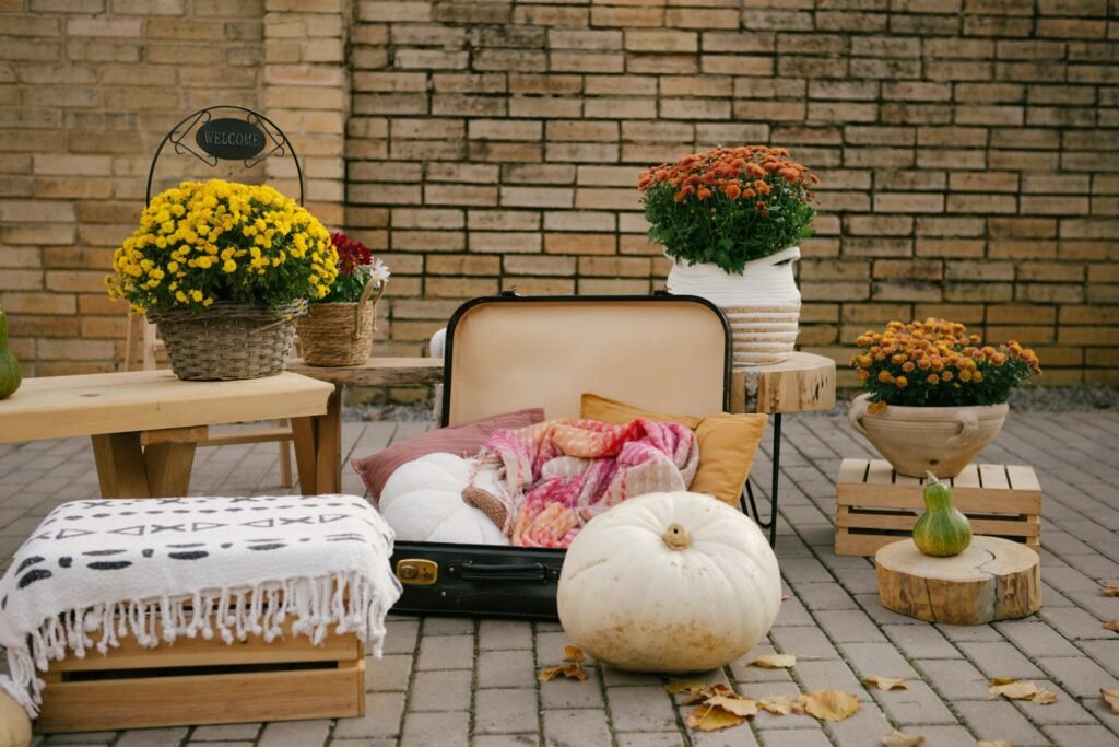 Autumn patio corner with pumpkins, mums and cushions.