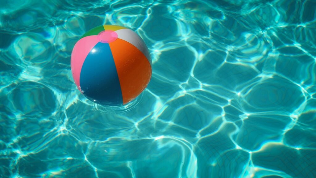 Beach ball floating in a bright blue swimming pool.