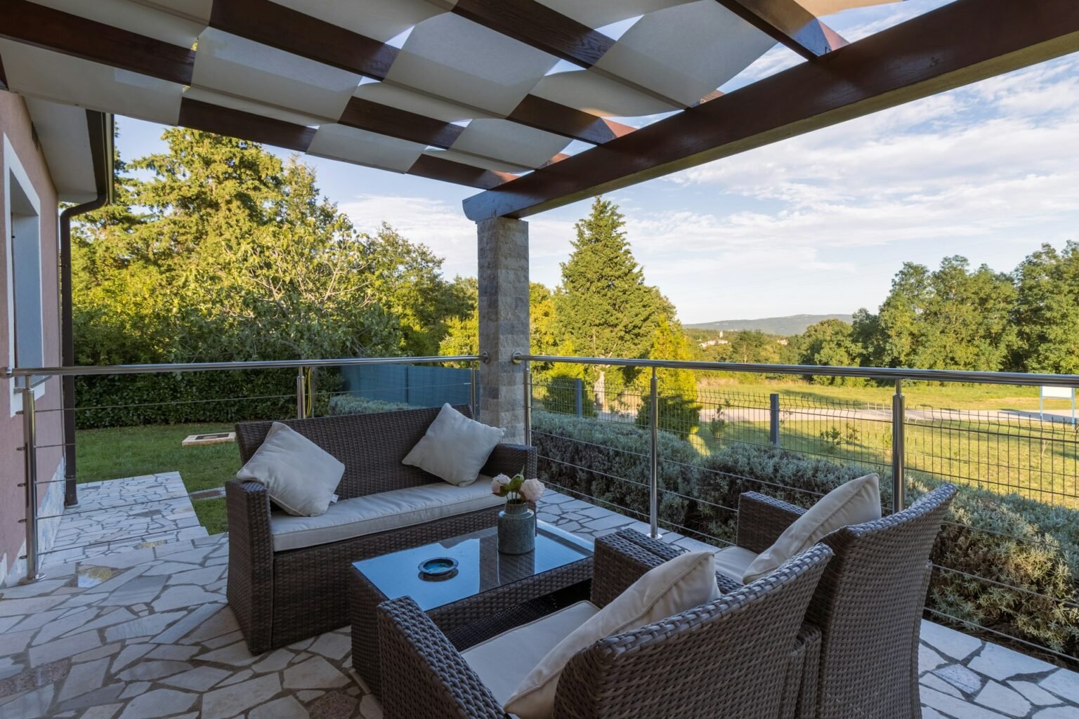 Stone patio under a pergola with wicker sofa and chairs