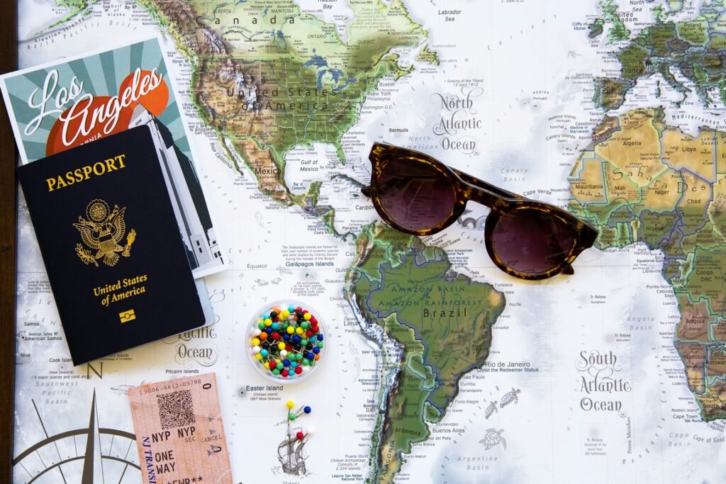 Passport, sunglasses and a world map laid out for travel planning.