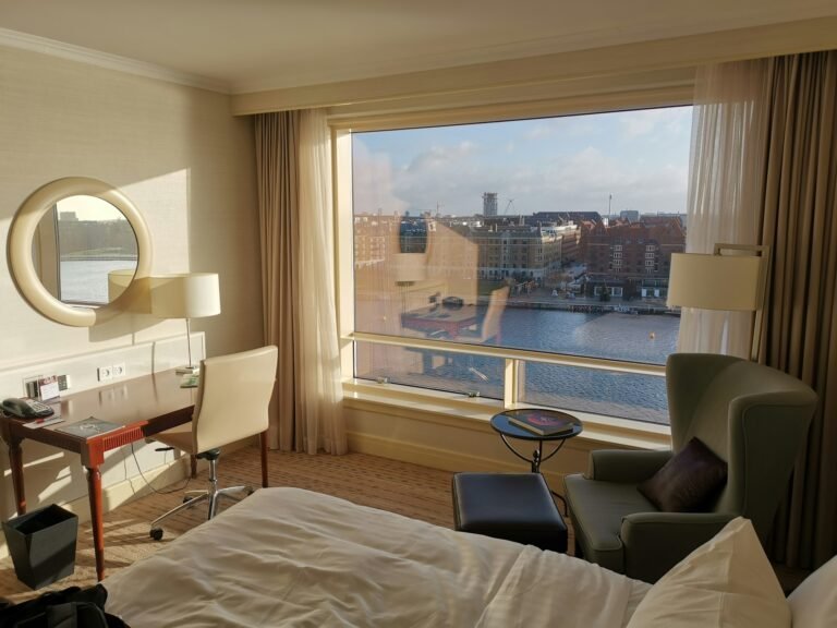 Bright hotel room with a large window and a harbor view