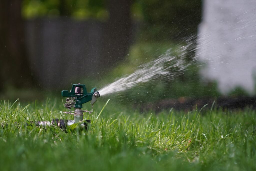 Sprinkler spraying water over a green lawn.